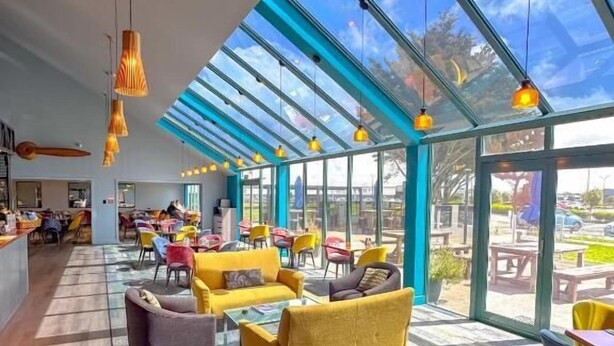 A spacious indoor area with a high ceiling, large windows, and modern furniture.