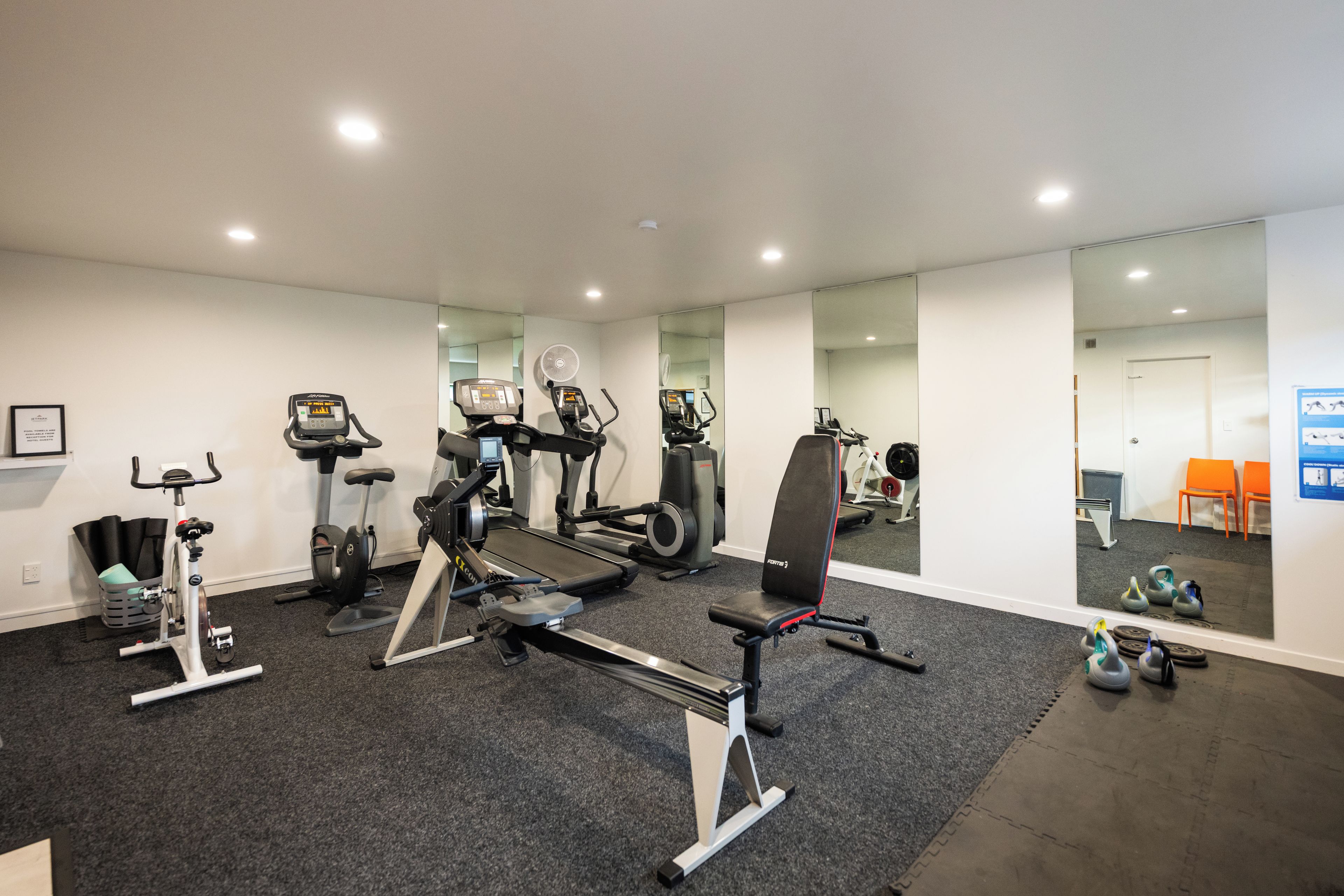 Une salle de sport équipée de divers appareils d’exercice, notamment des tapis de course, des vélos d’appartement et des poids.