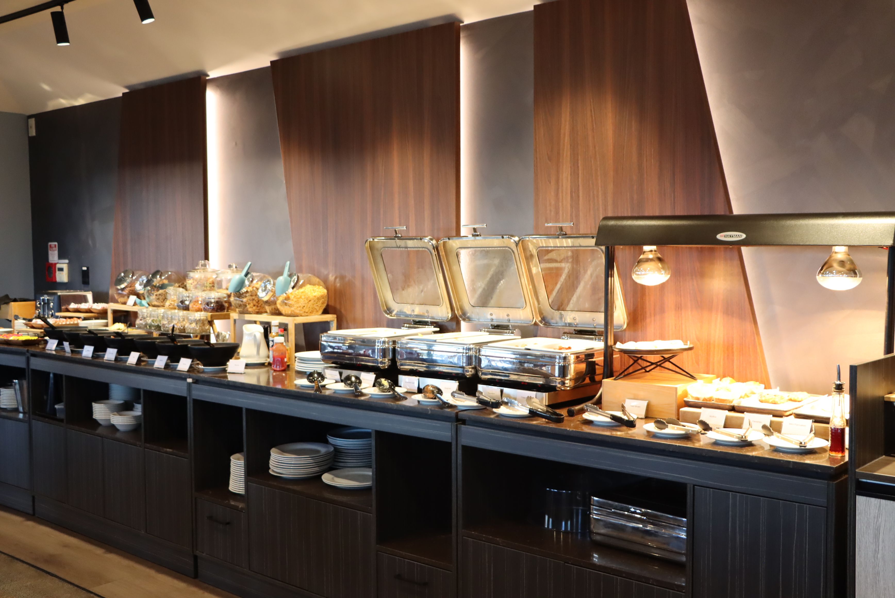 Disposição de buffet com várias estações de serviço, incluindo recipientes de vidro e utensílios.