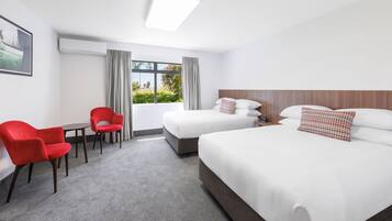 Habitación de hotel con dos camas, un escritorio y sillas.