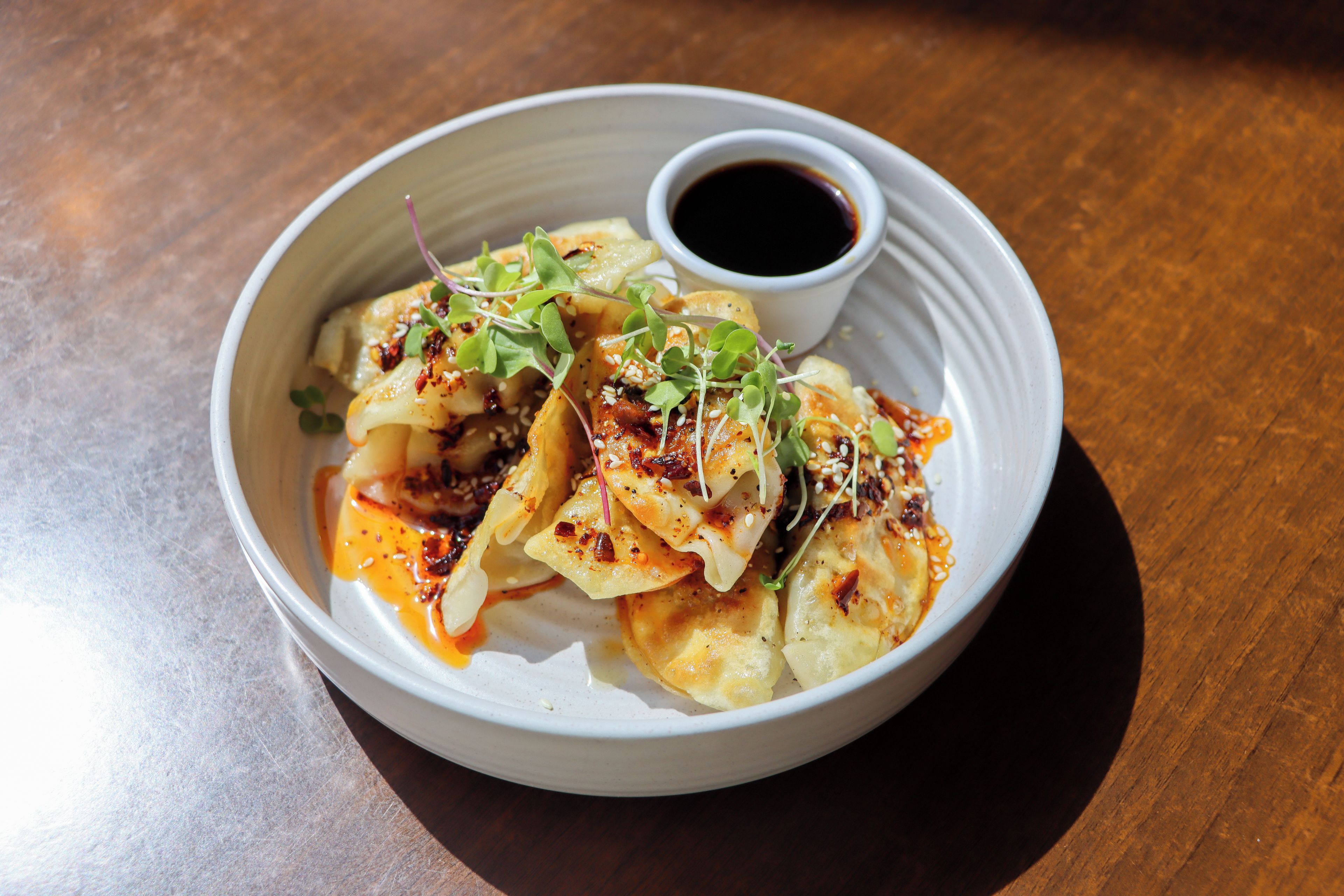 A plate of food with a side of sauce and a small cup of soy sauce.