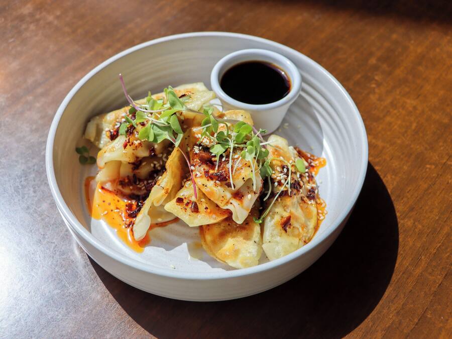 A plate of food with a side of sauce and a small cup of soy sauce.