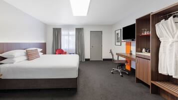 Une chambre d’hôtel avec un lit, un bureau, une chaise, une télévision, une armoire et une porte.