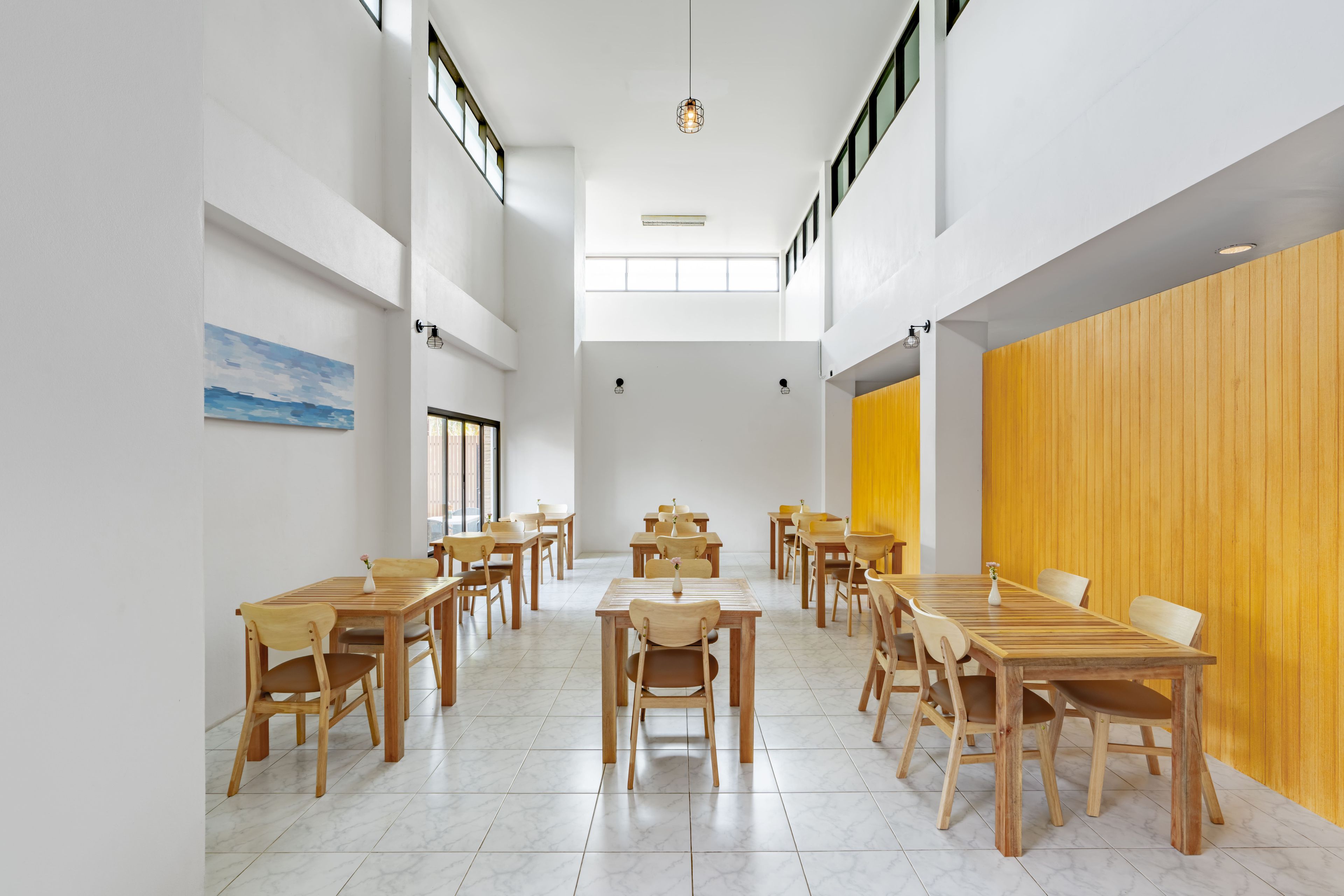A spacious dining area with high ceilings, natural light from windows, and a mix of wooden and white walls.
