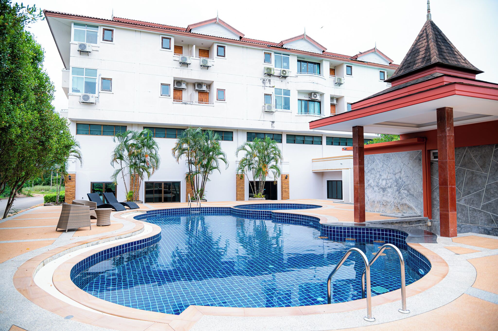A swimming pool with a curved design, surrounded by lounge chairs and palm trees.
