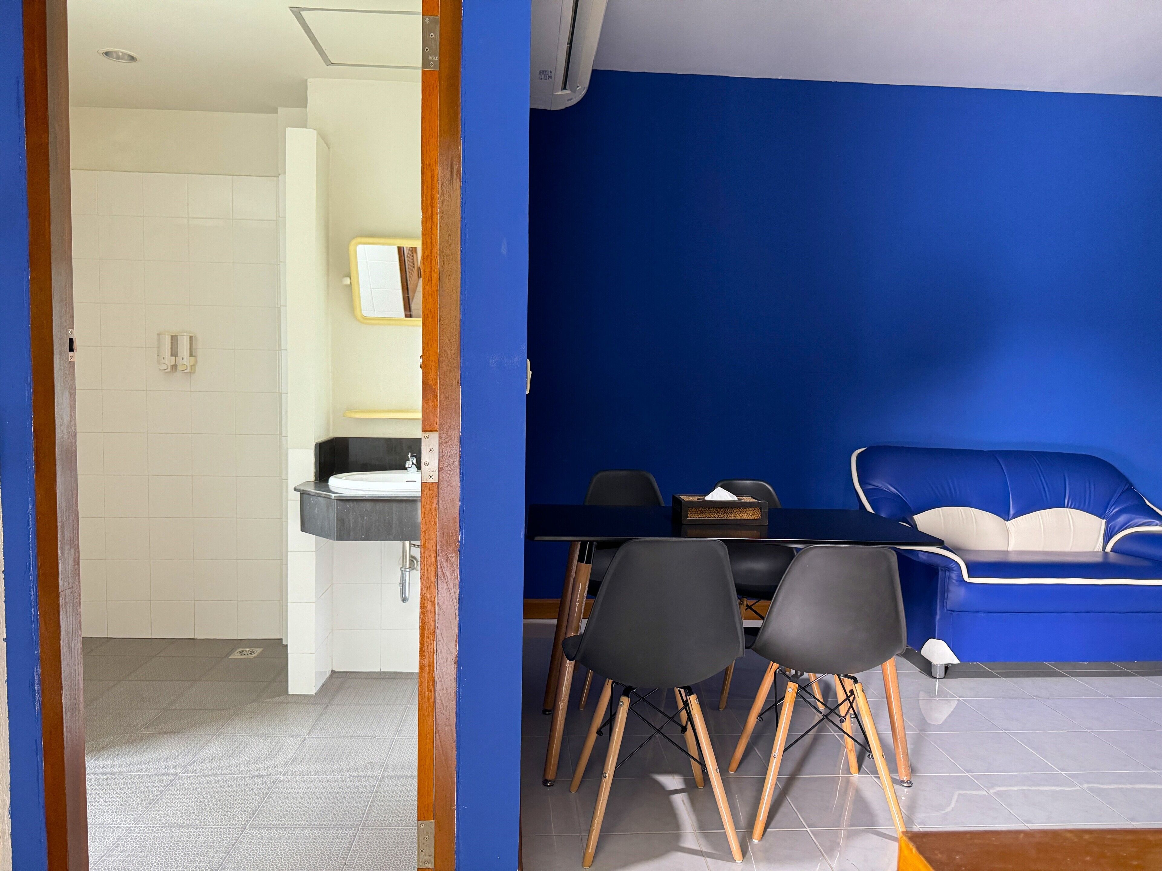 A room with a blue wall, a white sink, and a black table with chairs.