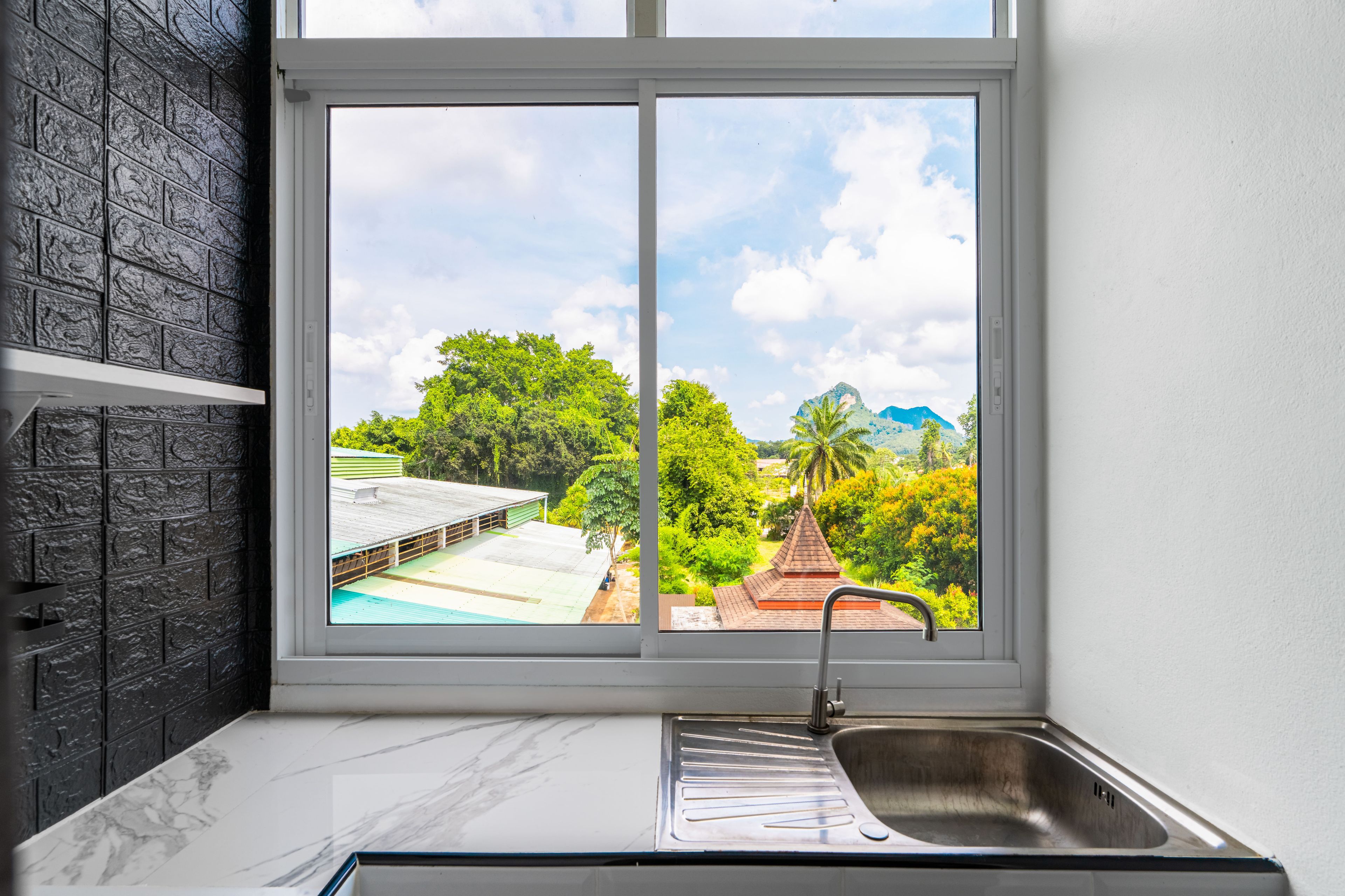 A kitchen with a large window, a sink, and a marble countertop.