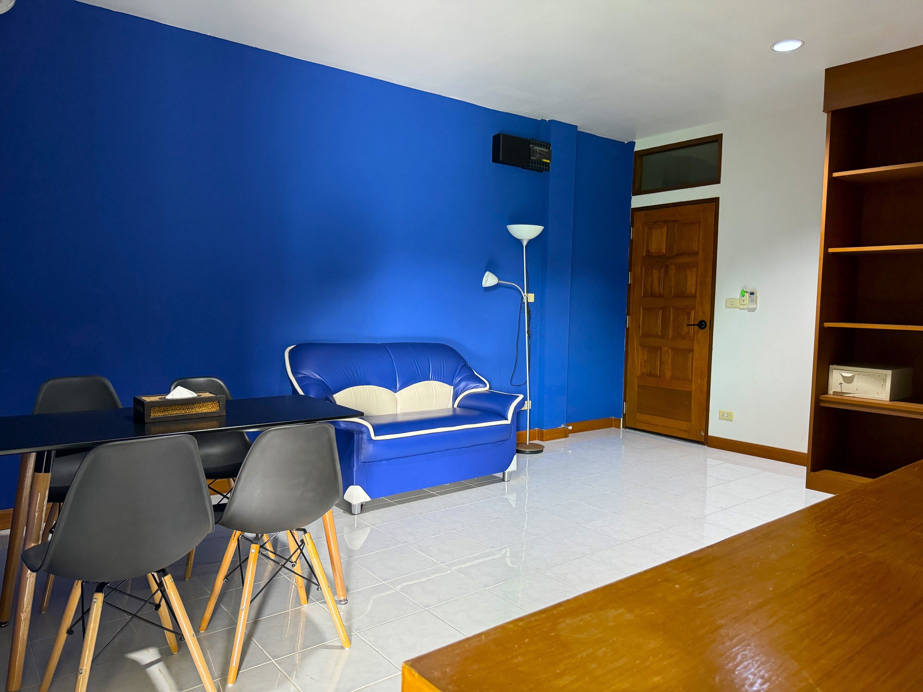 Een kamer met een blauwe wand, een houten deur, een wit plafond en een betegelde vloer.