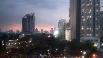 A cityscape at dusk with high-rise buildings, one with a construction crane, and a busy street with vehicles.