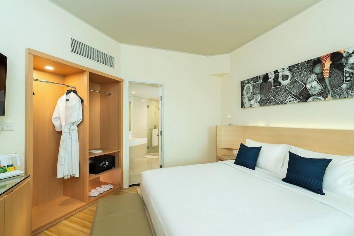 A hotel room with a bed, a walk-in closet, a bathroom, and a wall-mounted artwork.