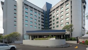A modern hotel with a central atrium, multiple floors, and a parking lot. - Cityloog Hotel Tebet Jakarta (Jakarta)