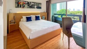 A modern hotel room with a large bed, a chair, a desk, and a balcony with a view of the city. - Cityloog Hotel Tebet Jakarta (Jakarta)