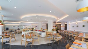 A modern restaurant with a central island, wooden tables, and chairs. - Cityloog Hotel Tebet Jakarta (Jakarta)