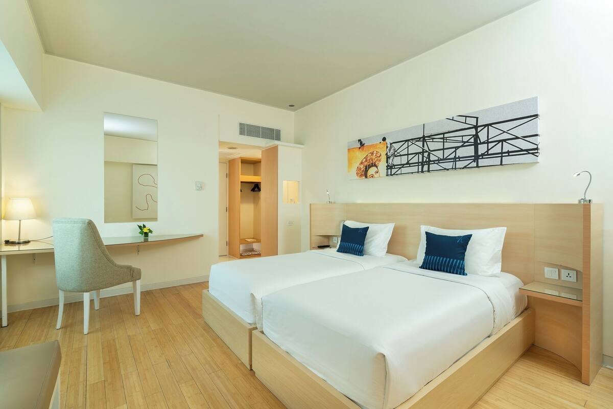 A hotel room with a large bed, a desk, a chair, and a mirror.