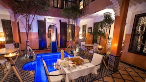 A poolside dining area with a checkered floor, a pool, and a table set for a meal. - Riad Alaka (Marrakech)
