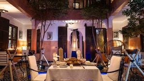 An outdoor dining area with a pool table, chairs, and a table set for a meal. - Riad Alaka (Marrakech)