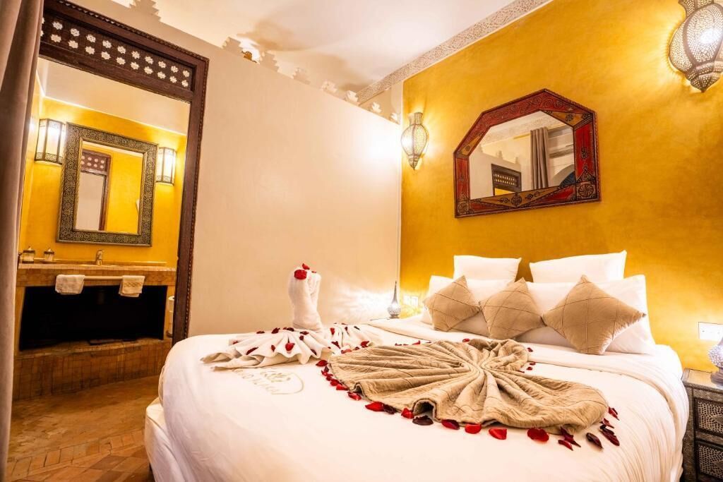 Ein Hotelzimmer mit einem großen Bett, einem Badezimmer mit Waschtisch und einem Spiegel.