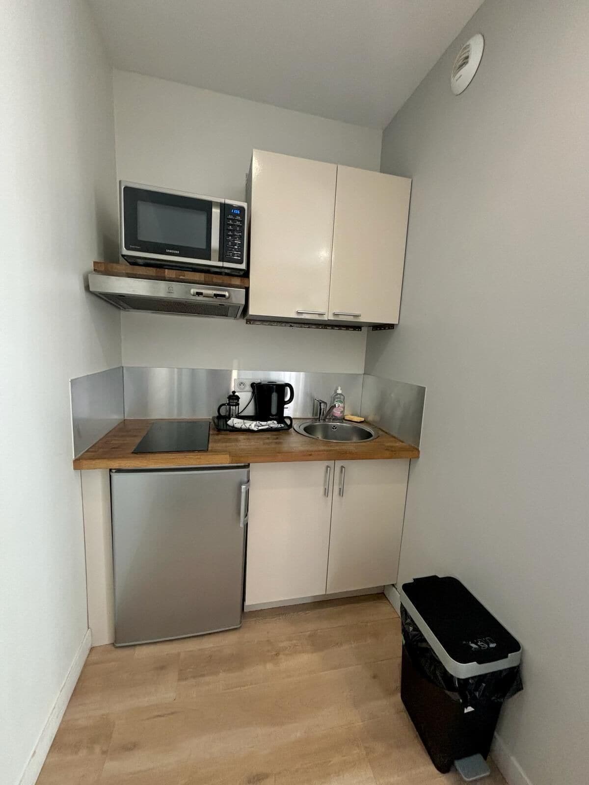 Een kleine keuken met een magnetron, koffiezetapparaat en spoelbak.