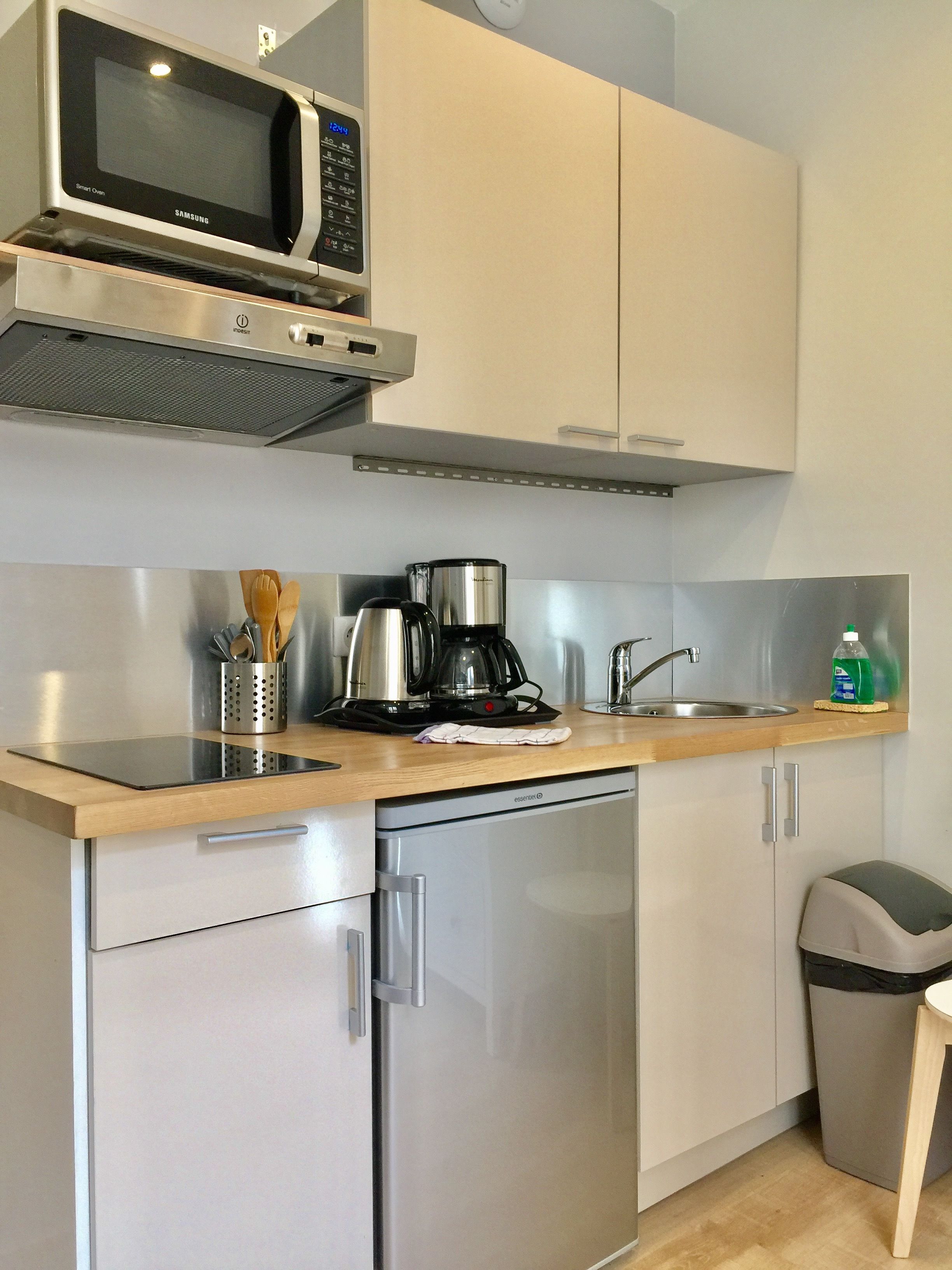 A compact kitchen with a microwave, coffee maker, sink, and dishwasher.