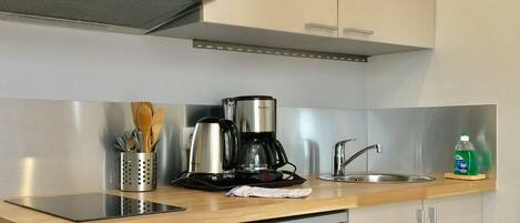 A compact kitchen with a microwave, coffee maker, sink, and dishwasher.