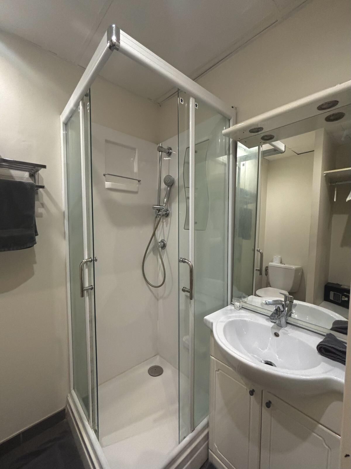 Un bagno moderno con doccia vetrata, lavandino bianco e specchio sopra.