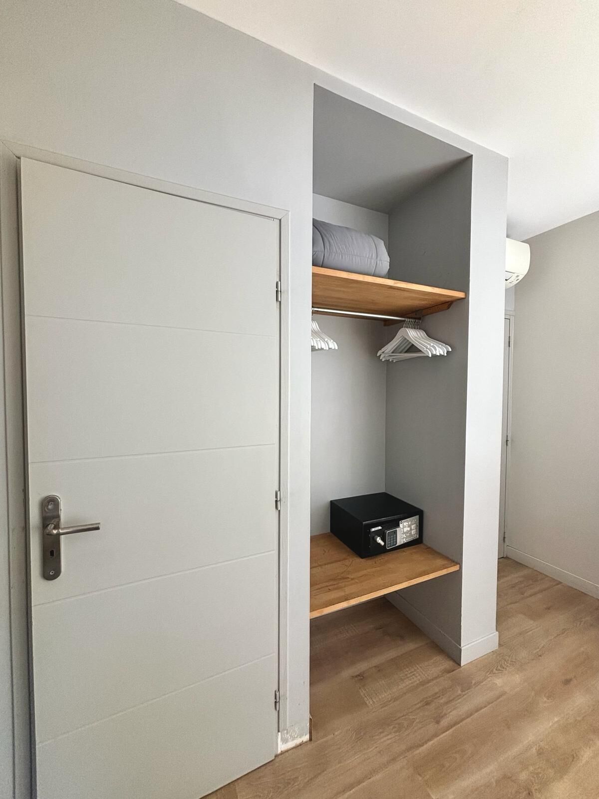 A room with a white door, a grey wall, and a wooden floor.