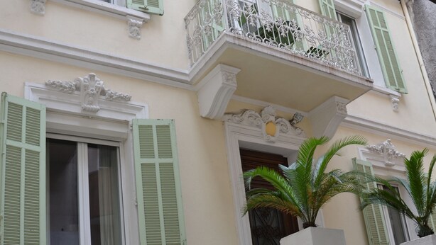 A building with multiple balconies, green shutters, and white railings. - Rent Cannes Meublés Gambetta (Cannes)