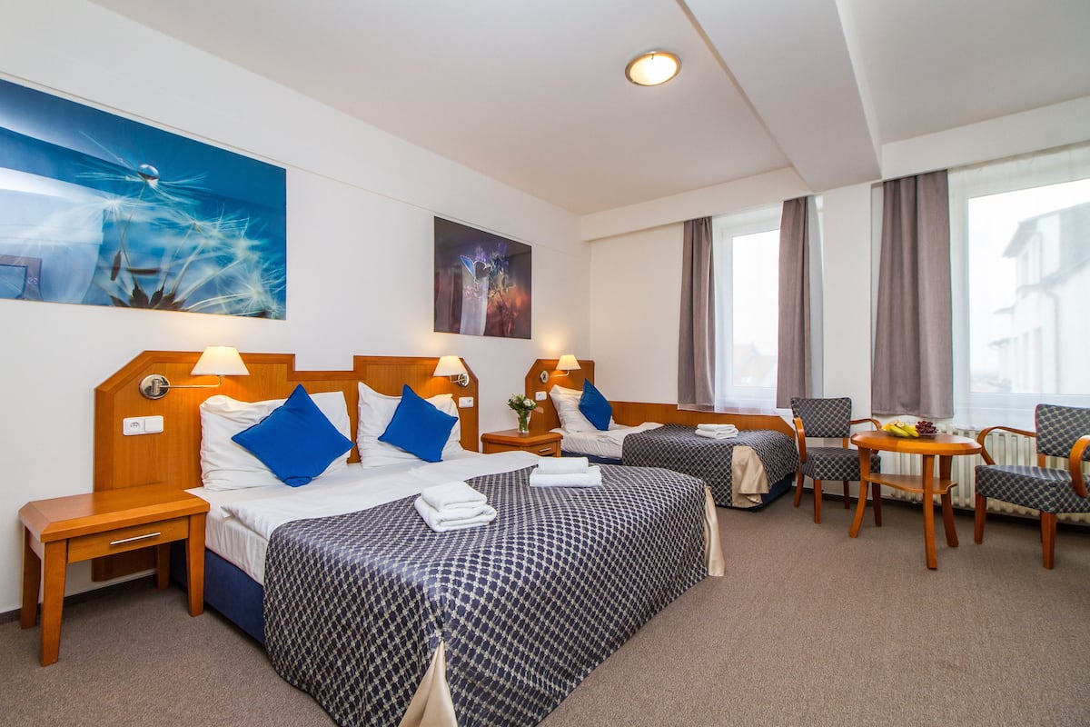 Habitación de hotel con dos camas, una mesita con fruta y una silla.