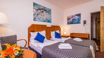 A hotel room with two beds, a wooden headboard, a desk with a lamp, and a chair.
