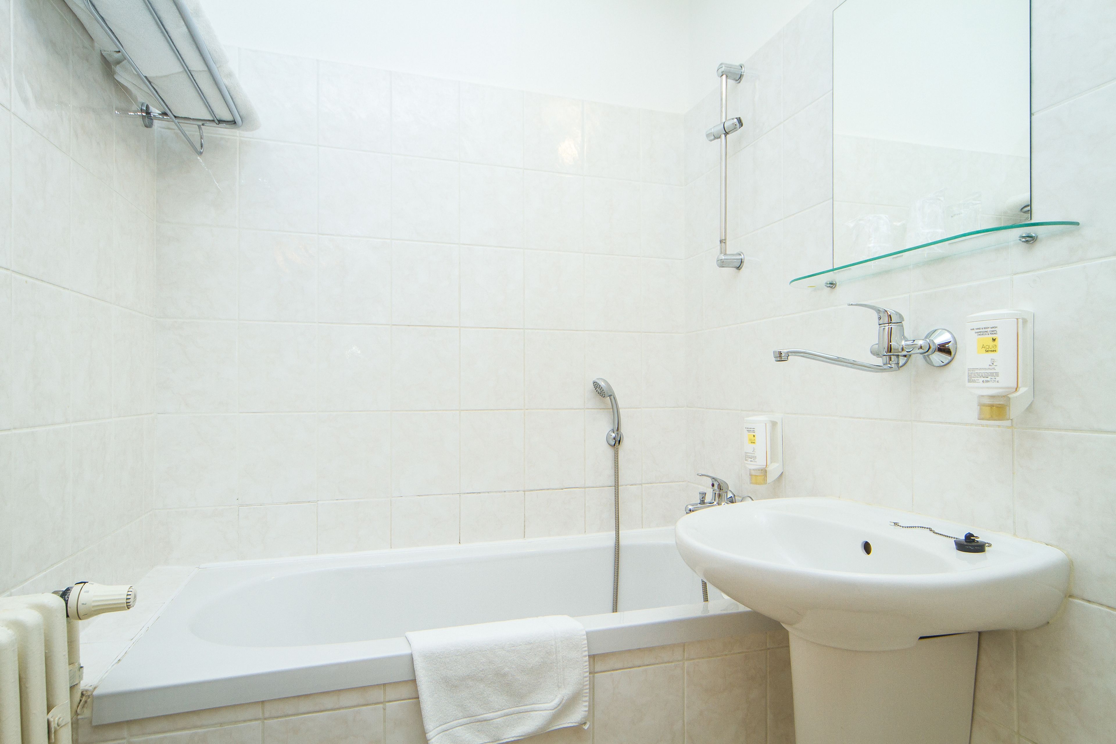 Un baño con bañera, lavabo, estante de vidrio y espejo.