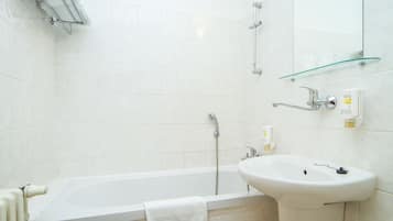 A bathroom with a bathtub, a sink, a glass shelf, and a mirror.