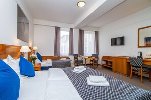 Une chambre d’hôtel avec deux lits, un bureau, une chaise, une télévision et une fenêtre avec des rideaux.