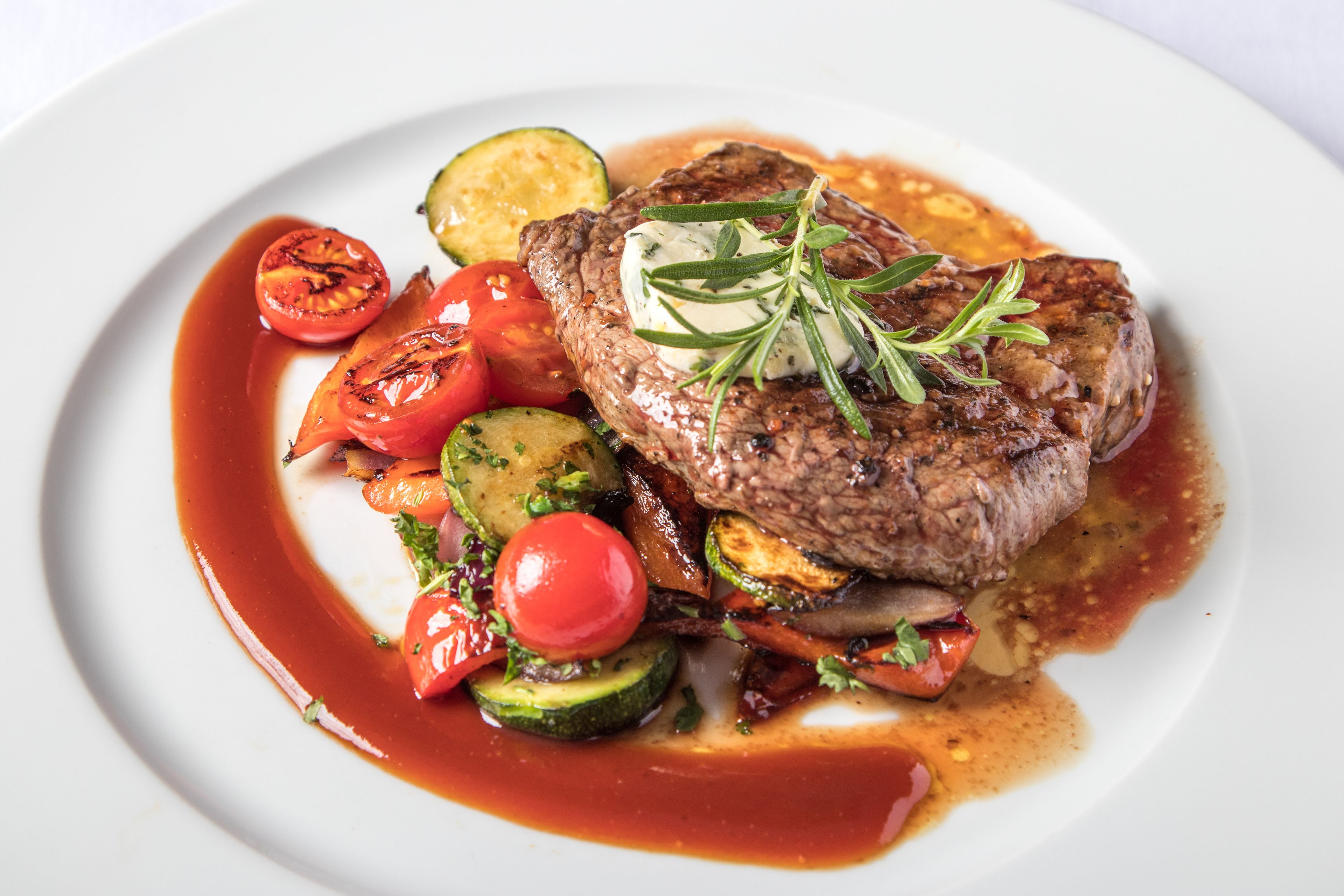 Ein Steak mit Gemüse und Soße auf einem Teller.
