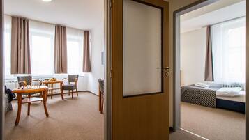 A hotel room with a bed, a desk, two chairs, and a small table.