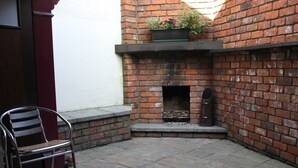 Un patio con pared de ladrillo, una chimenea y una silla de metal.