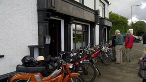 Una hilera de motocicletas antiguas estacionadas frente a un edificio con un cartel que dice 'The Olde Inn'.