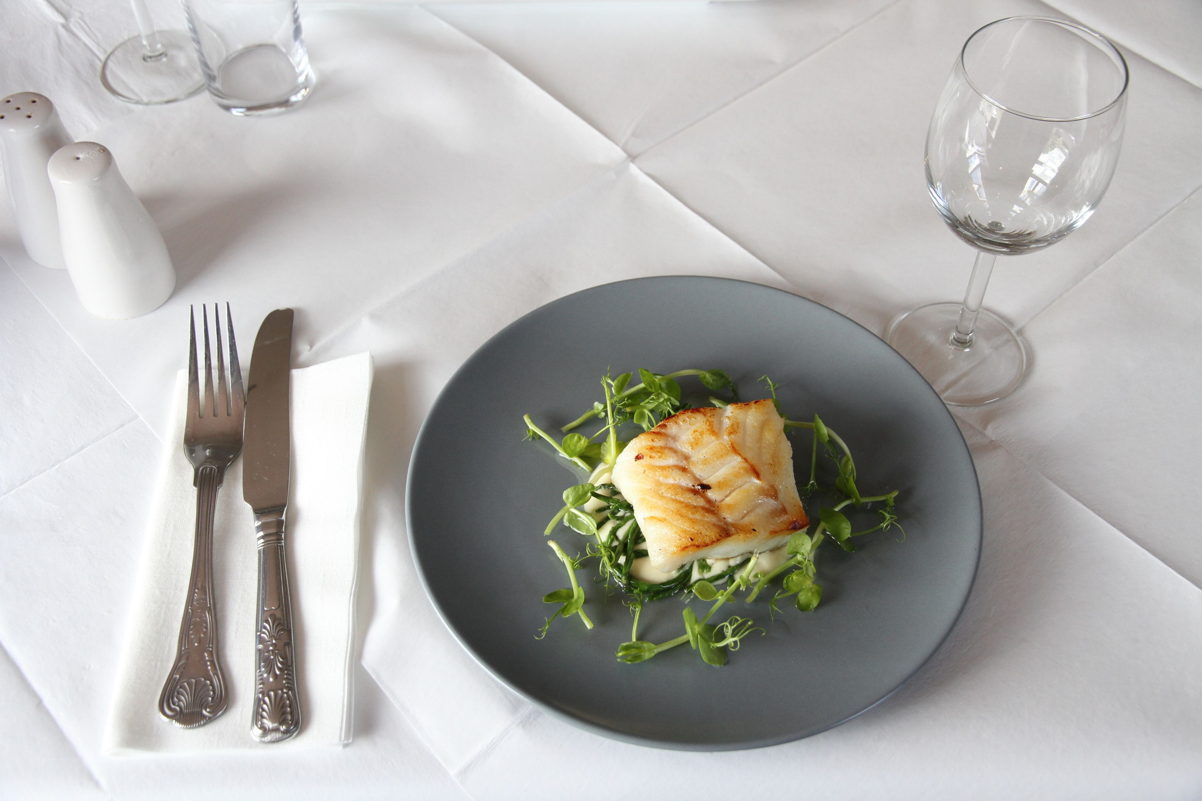 A plate of food with a fork and knife on a white tablecloth.