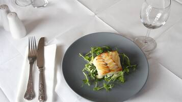 A plate of food with a fork and knife on a white tablecloth.