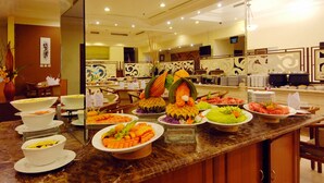 A buffet with various dishes and a television in the background. - Singgasana Hotel Makassar (Makassar)