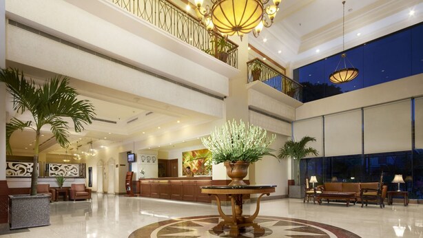 A spacious lobby with a reception desk, seating area, and a large decorative plant. - Singgasana Hotel Makassar (Makassar)