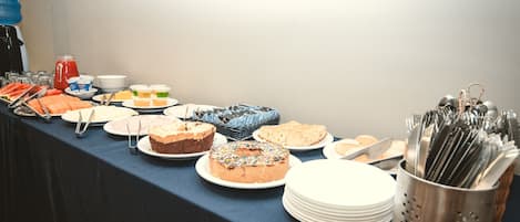 A buffet table with various food items and utensils.