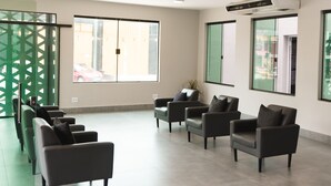 Un vaste espace d’attente doté de plusieurs fauteuils en cuir, de grandes fenêtres et d’un panneau de séparation vert.