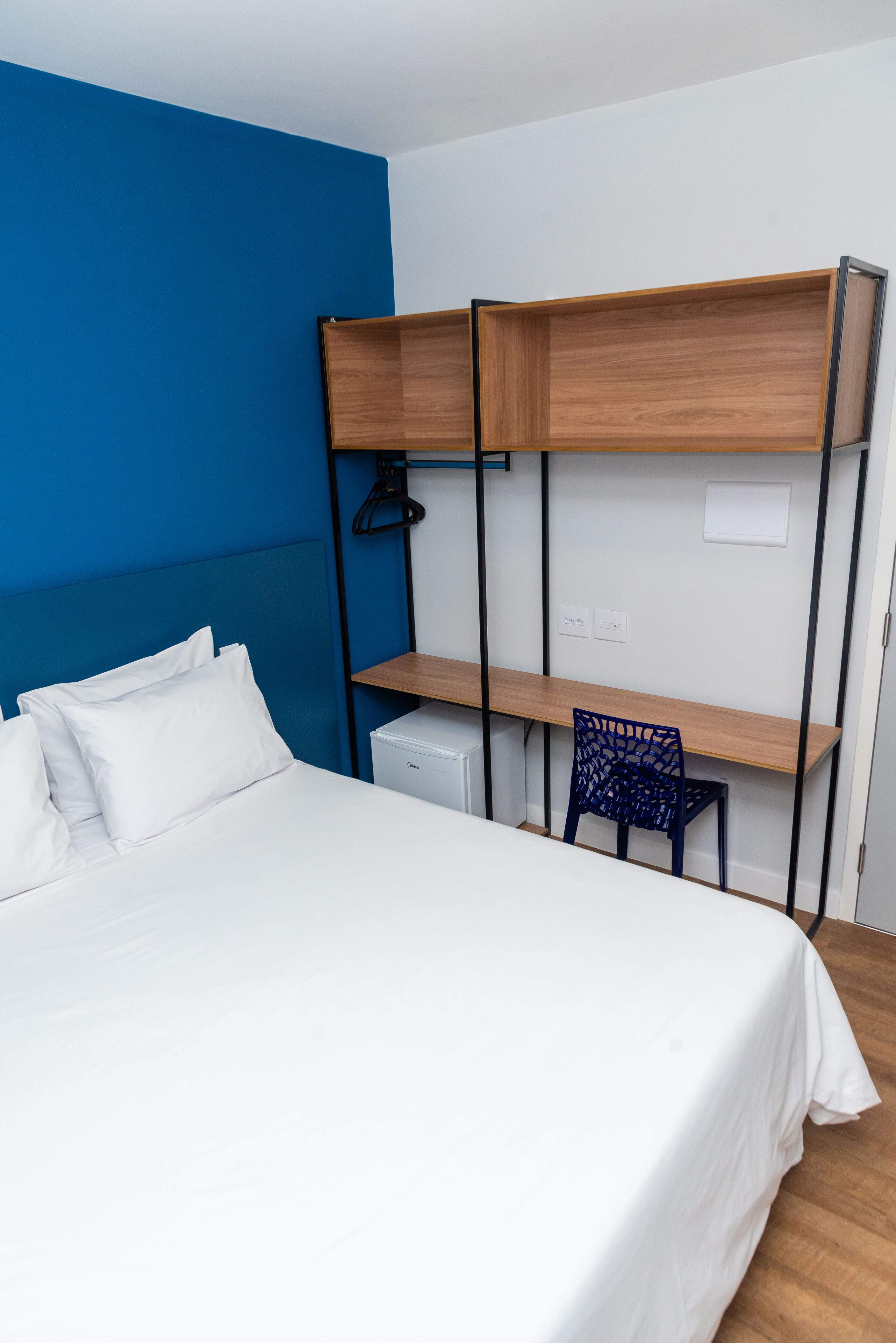 Une pièce comprenant un lit, un bureau avec une chaise et un radiateur.