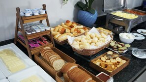 A buffet with various food items including bread, pastries, and condiments. - Plaza Inn Trevo Sorocaba (Sorocaba)