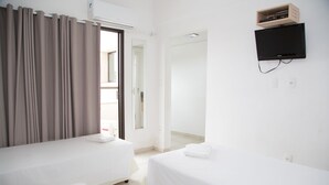 Une chambre d’hôtel avec deux lits, un téléviseur fixé au mur et une porte coulissante donnant sur un balcon.