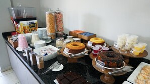 Un buffet proposant une variété de plats, notamment des gâteaux, des beignets et des boissons.