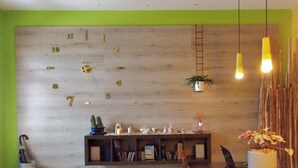 Un salon moderne avec une horloge murale en bois, une bibliothèque, une table à manger et des luminaires suspendus.