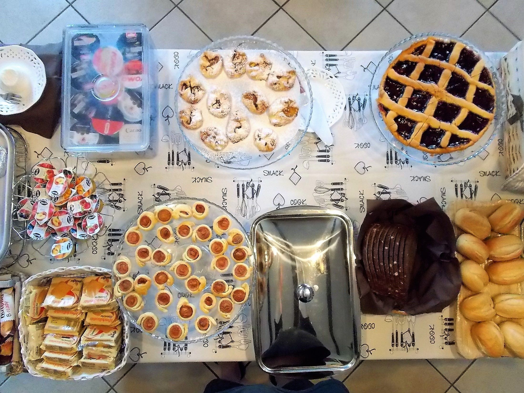 A table with various food items including pies, pastries, and a tray of cookies.