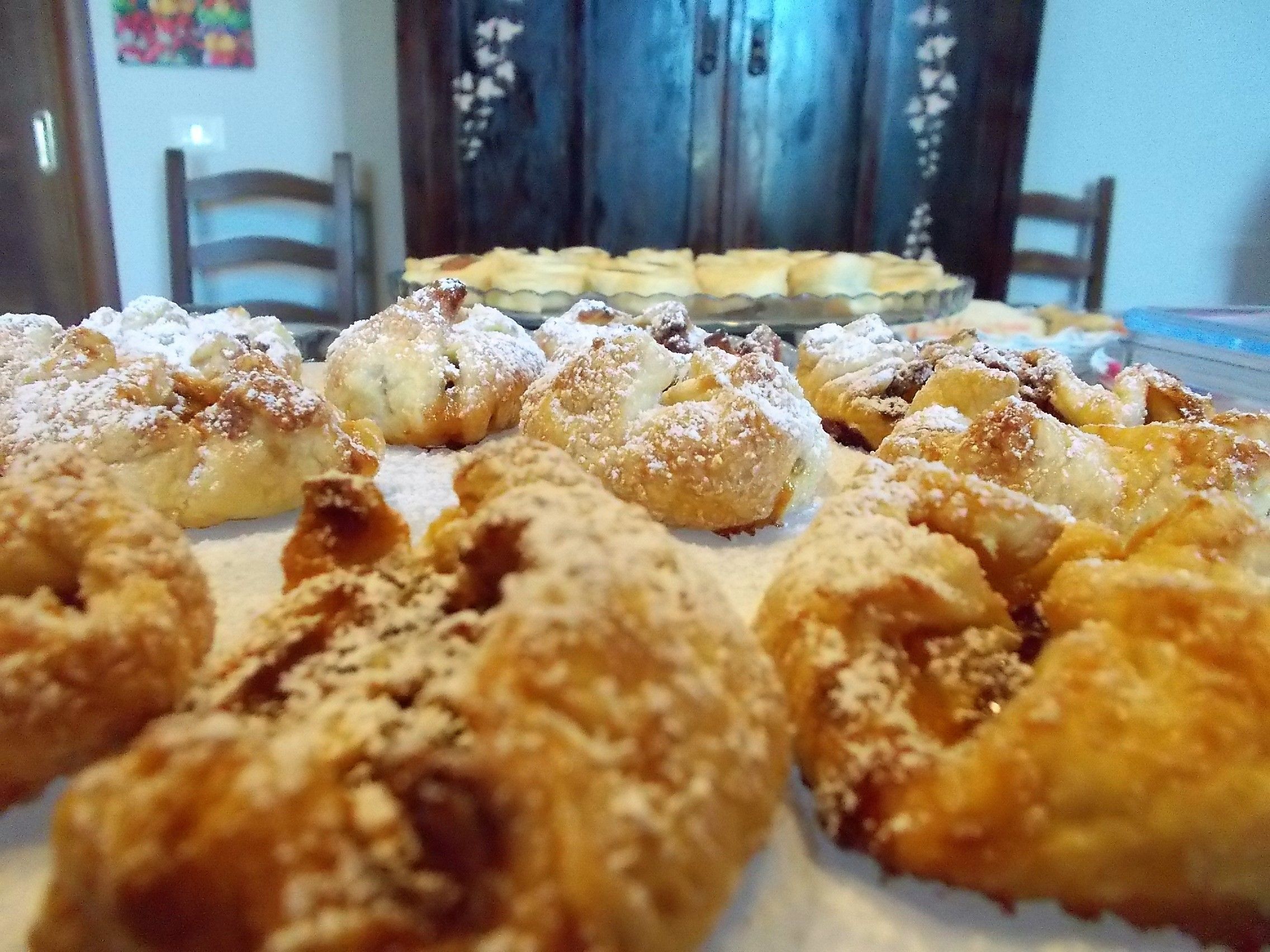 Et bord med forskellige kager, herunder doughnuts og kager drysset med flormelis.