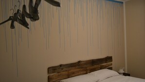 Une chambre à coucher avec une tête de lit en bois, un lit blanc et un mur orné de lignes verticales.